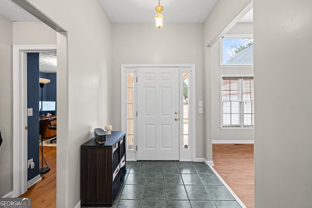 foyer entrance with baseboards and dark wood-style flooring