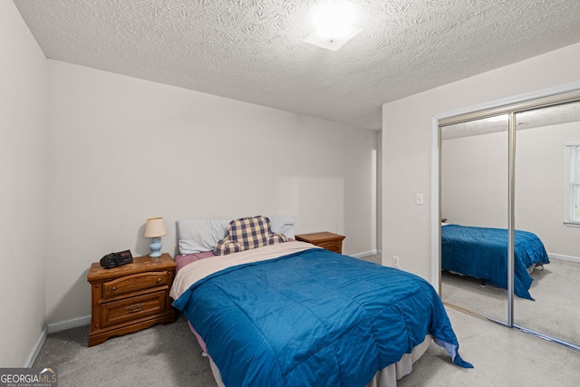 bedroom with a closet, baseboards, a textured ceiling, and carpet floors