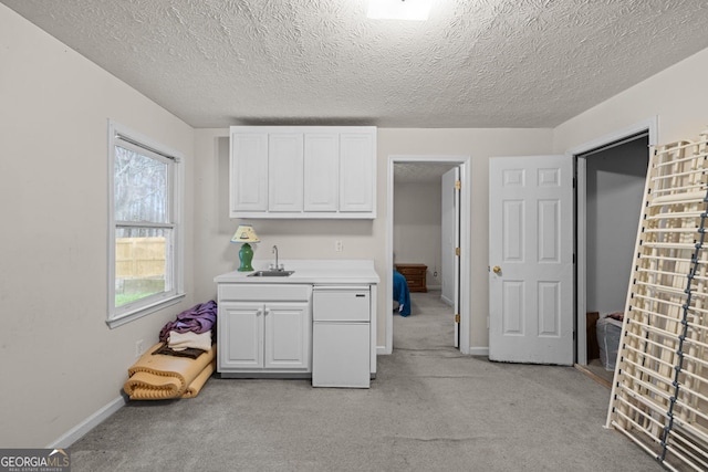 kitchen with light colored carpet, refrigerator, light countertops, and white cabinetry