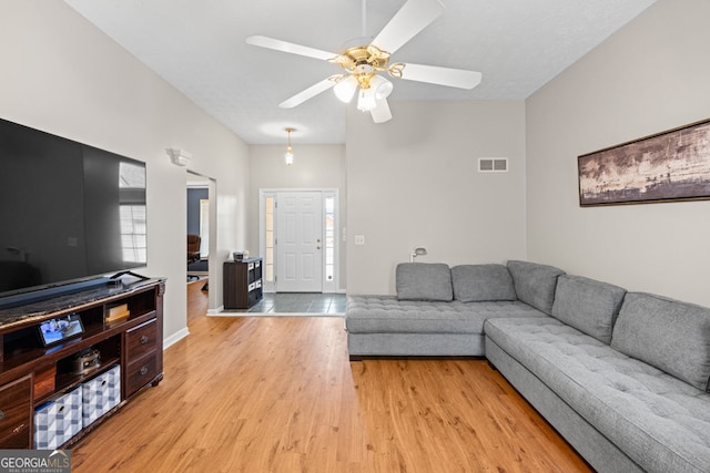 living room with light wood finished floors, visible vents, and a ceiling fan