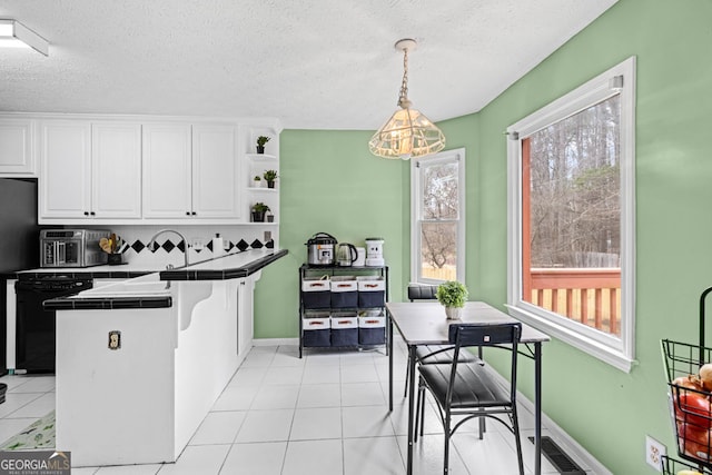 kitchen featuring light tile patterned floors, open shelves, tile counters, white cabinetry, and stainless steel microwave