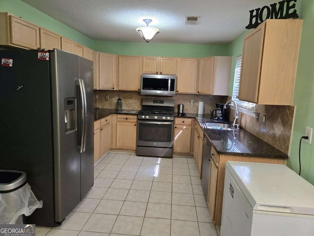 kitchen with visible vents, light brown cabinetry, a sink, stainless steel appliances, and light tile patterned floors