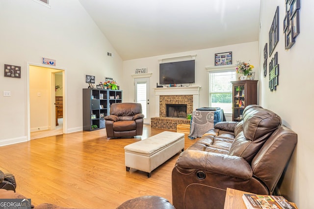 living area with plenty of natural light, high vaulted ceiling, wood finished floors, and a fireplace
