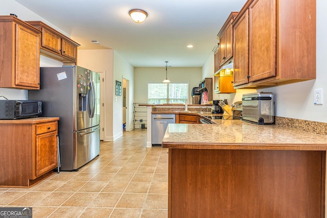 kitchen featuring brown cabinetry, a peninsula, appliances with stainless steel finishes, and hanging light fixtures