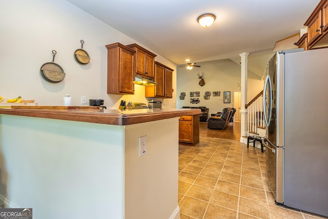 kitchen with freestanding refrigerator, a peninsula, under cabinet range hood, and brown cabinets