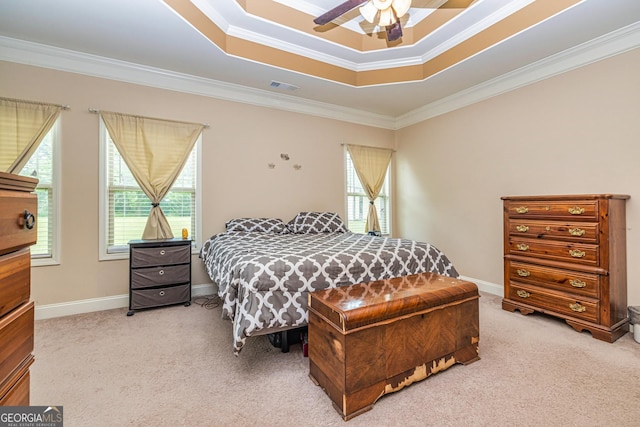carpeted bedroom featuring a ceiling fan, visible vents, crown molding, baseboards, and a tray ceiling