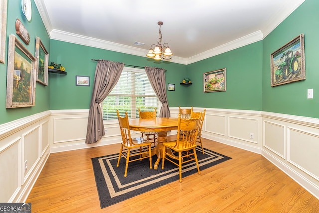 dining room featuring a notable chandelier, ornamental molding, wood finished floors, and visible vents