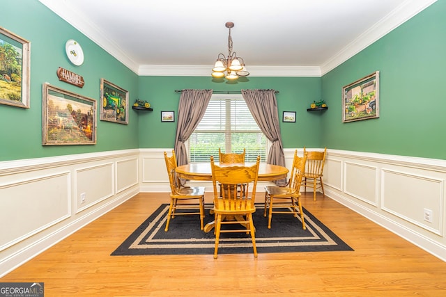 dining space with crown molding, wainscoting, wood finished floors, and a chandelier