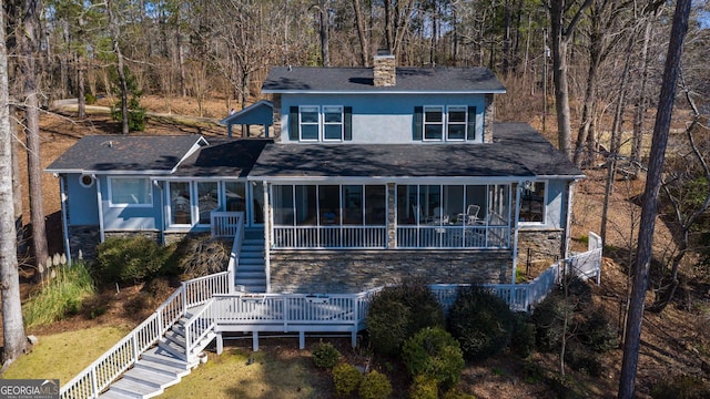 view of front of property with stucco siding, stone siding, stairway, and a sunroom