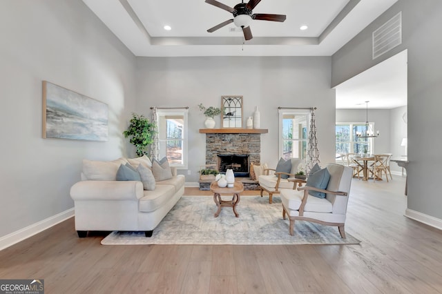 living room with a raised ceiling, wood finished floors, visible vents, and baseboards