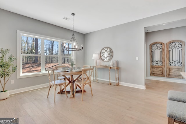 dining room featuring visible vents, baseboards, a chandelier, and light wood finished floors