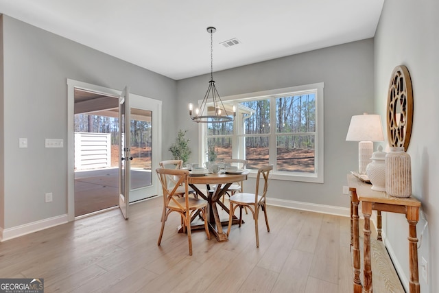 dining room with a wealth of natural light, visible vents, light wood finished floors, and an inviting chandelier