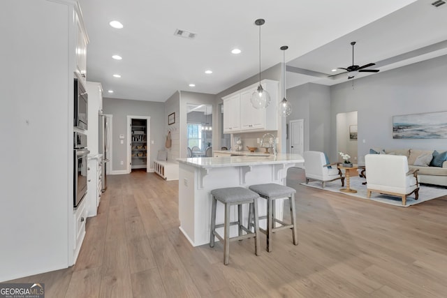 kitchen with visible vents, open floor plan, stainless steel appliances, a peninsula, and ceiling fan