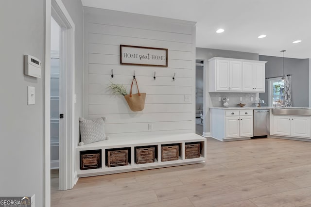 mudroom featuring wooden walls, recessed lighting, light wood-style floors, and a sink