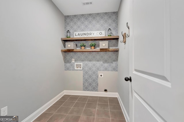 washroom featuring electric dryer hookup, baseboards, an accent wall, and laundry area