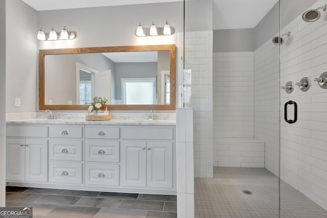 full bath featuring double vanity, tiled shower, and a sink