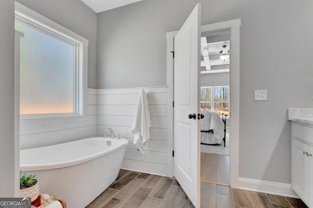 full bath featuring a freestanding bath, vanity, wood finish floors, and a ceiling fan