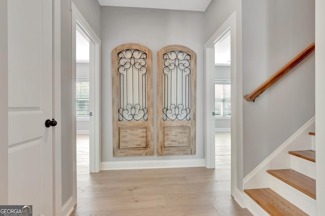 foyer featuring stairway, baseboards, and light wood-style flooring