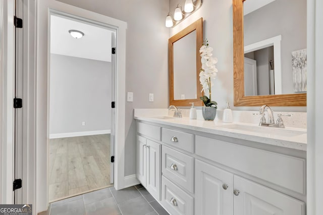 bathroom featuring a sink, baseboards, double vanity, and tile patterned flooring