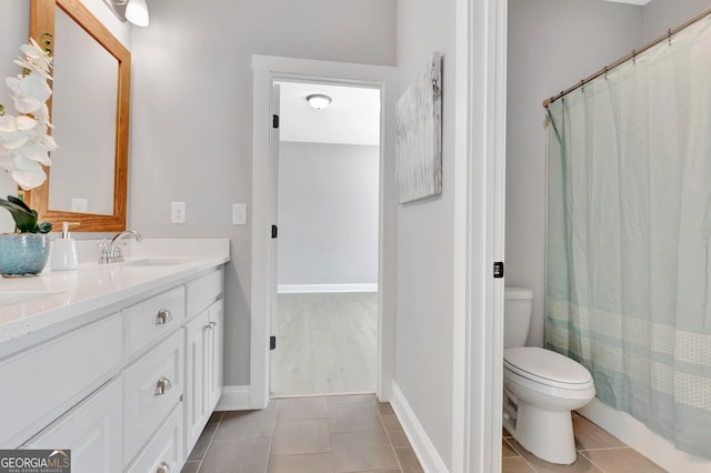 bathroom with tile patterned flooring, toilet, vanity, and baseboards