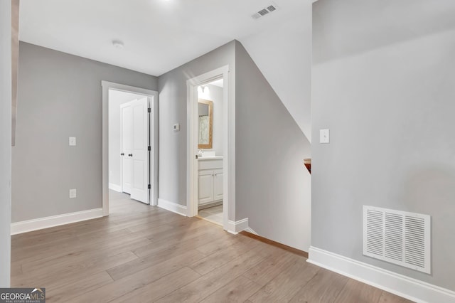 interior space featuring light wood-type flooring, visible vents, and baseboards