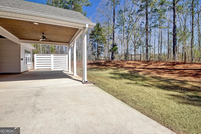 view of yard featuring an attached carport, ceiling fan, and driveway