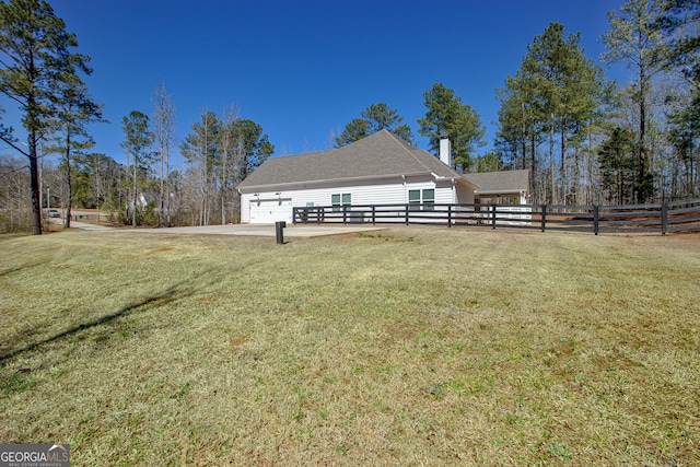 view of yard featuring driveway, a garage, and fence