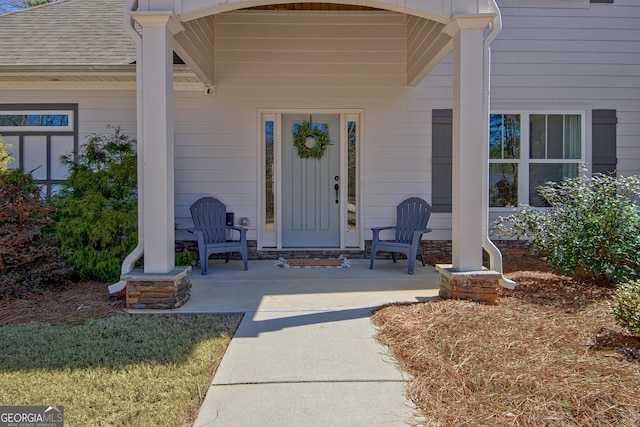 entrance to property with a porch and roof with shingles