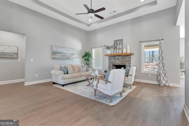 living area featuring wood finished floors, visible vents, a fireplace, ceiling fan, and a towering ceiling