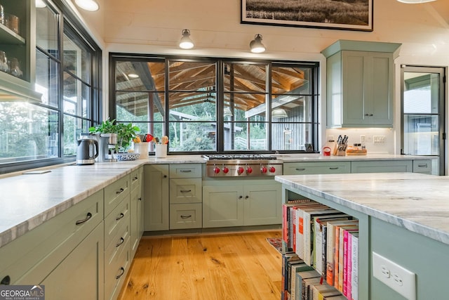 kitchen with green cabinets, stainless steel gas stovetop, and light wood-style floors