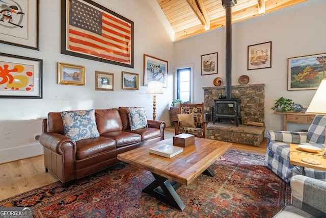 living room featuring wood finished floors, high vaulted ceiling, beam ceiling, a wood stove, and wood ceiling