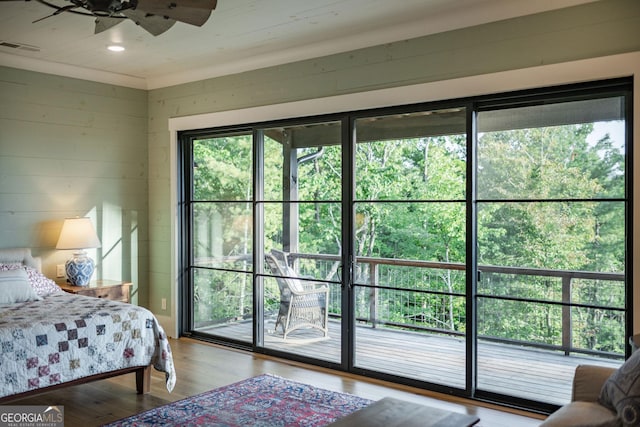 bedroom with wooden walls, wood finished floors, visible vents, recessed lighting, and access to exterior