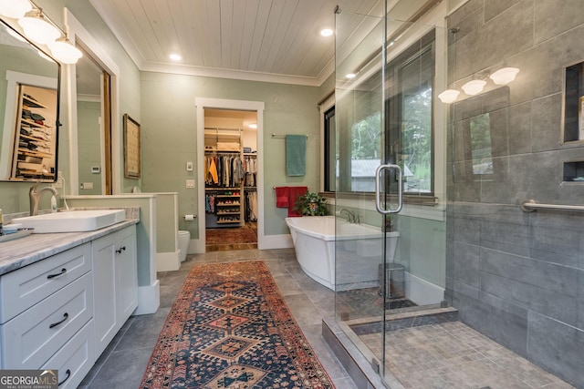 bathroom featuring a shower stall, a walk in closet, a freestanding bath, ornamental molding, and vanity