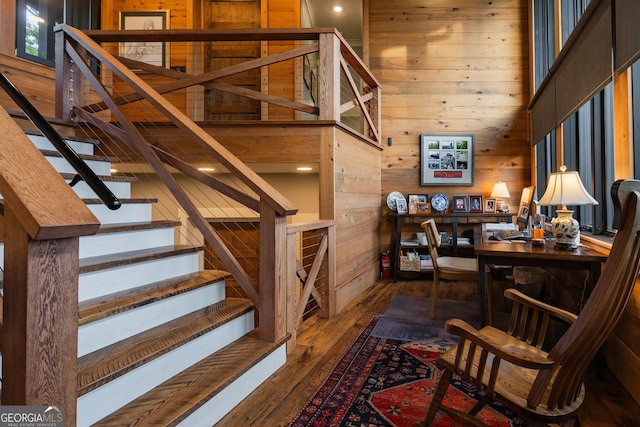 stairs with wooden walls, a towering ceiling, and hardwood / wood-style flooring