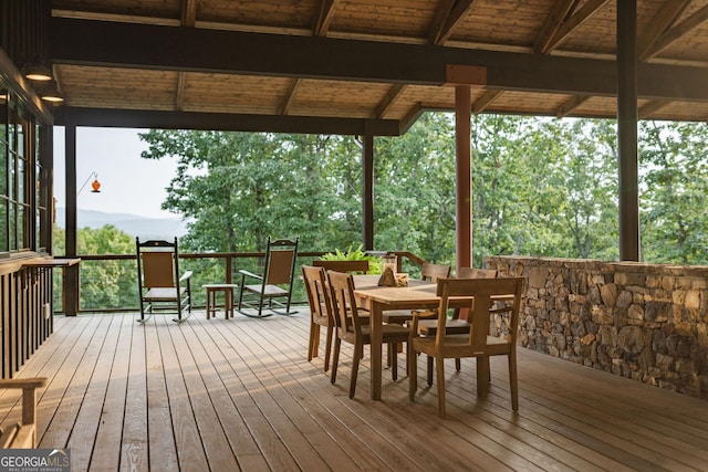 wooden terrace with outdoor dining area and a mountain view