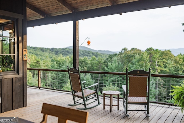 wooden terrace featuring a view of trees