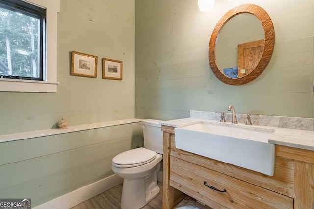 half bathroom featuring toilet, vanity, and wood finished floors