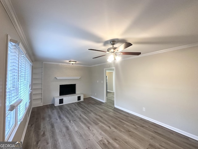 unfurnished living room with a ceiling fan, baseboards, a fireplace with raised hearth, dark wood-type flooring, and crown molding