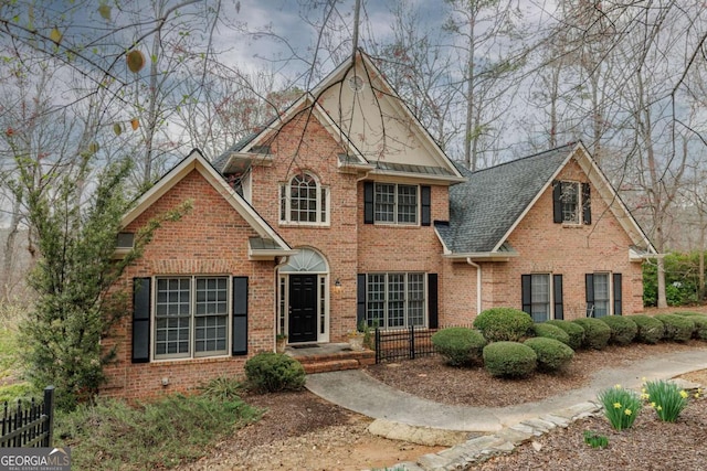 view of front of home featuring brick siding, a shingled roof, and fence