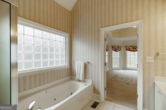 bathroom with tile patterned flooring, a tub with jets, and wallpapered walls