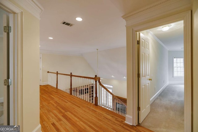 corridor with wood finished floors, an upstairs landing, visible vents, and ornamental molding