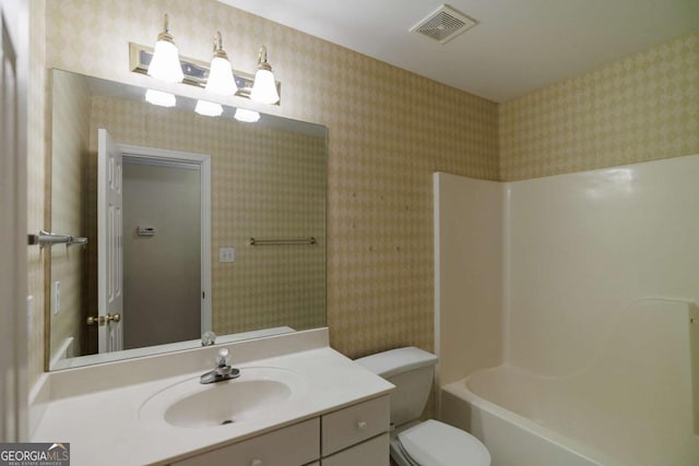 bathroom with visible vents, toilet, vanity, and wallpapered walls