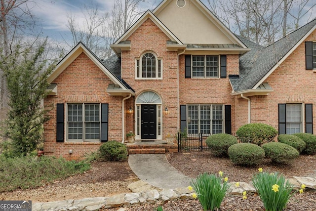 view of front of property with stucco siding, brick siding, and a shingled roof