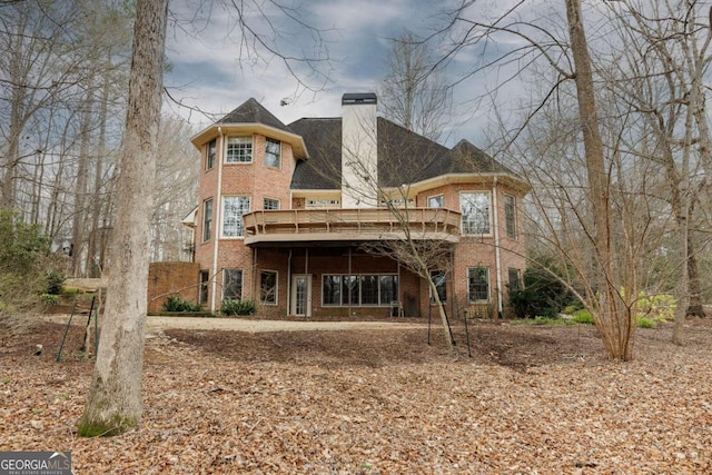 back of property featuring a wooden deck, brick siding, and a chimney