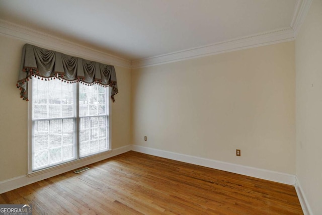 unfurnished room featuring visible vents, baseboards, wood finished floors, and crown molding