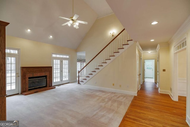 unfurnished living room with stairway, baseboards, high vaulted ceiling, and crown molding