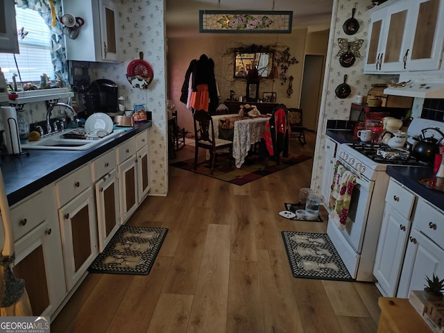 9 E Meadow Ln SW, Conyers, GA 30012 - kitchen featuring white gas range oven, wallpapered walls, dark countertops, light wood finished floors, and white cabinets