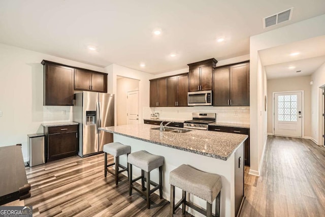 kitchen featuring dark brown cabinets, stainless steel appliances, visible vents, and light wood-style flooring