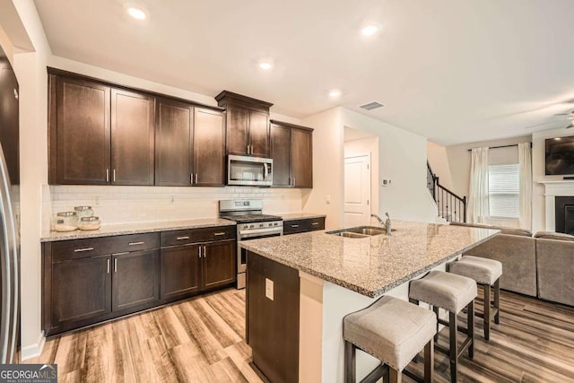 kitchen featuring visible vents, a breakfast bar, a sink, appliances with stainless steel finishes, and open floor plan