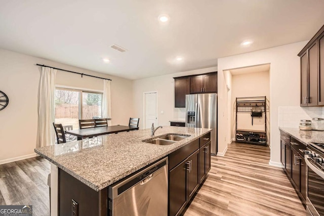 kitchen with visible vents, a sink, light stone counters, light wood-style floors, and appliances with stainless steel finishes